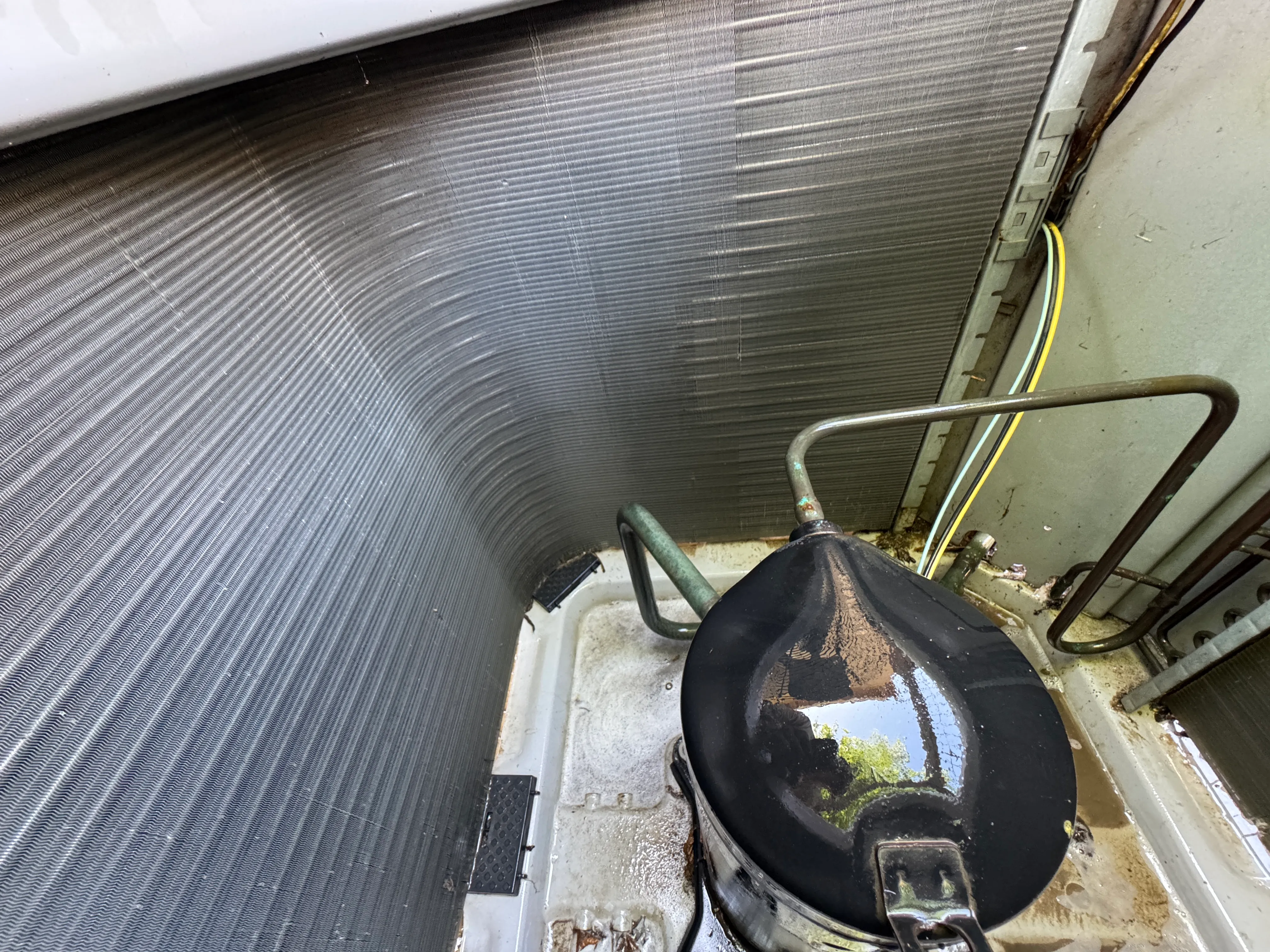 Inside a condenser after genuine maintenance at a Wildflower Climate visit: clean coil and tested components